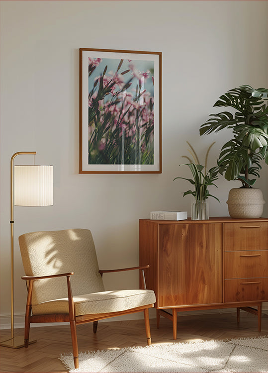 a cozy living room with a wooden cabinet, a beige armchair, a framed picture of pink flowers, and a potted plant.
