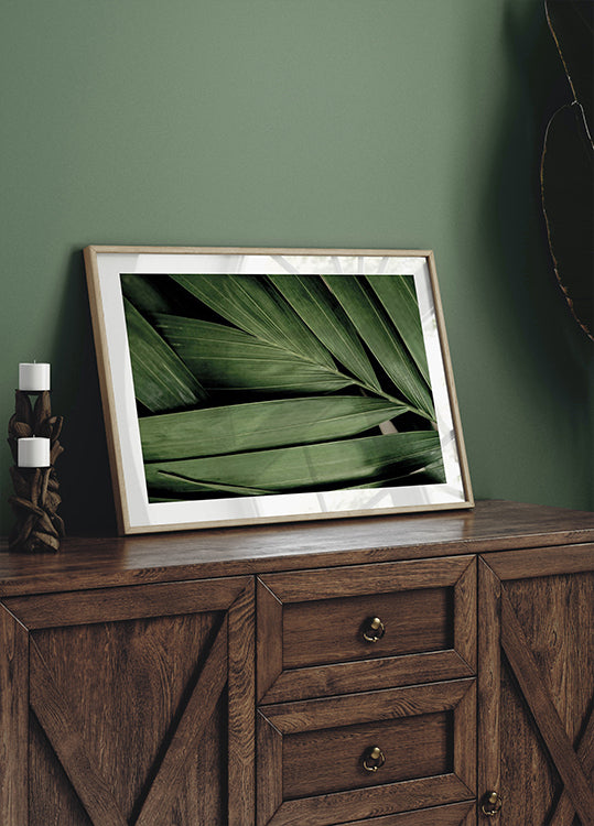 a picture of a green leaf in a frame on a dresser