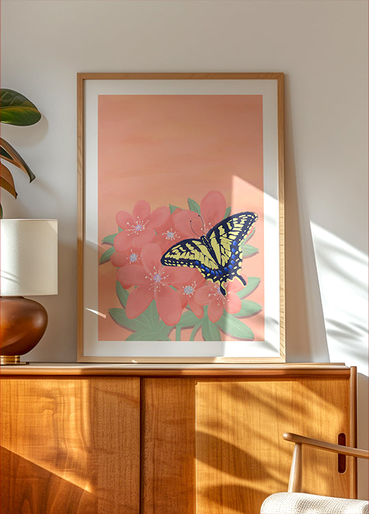 a framed painting of a butterfly on a pink flower, displayed on a wooden cabinet or shelf.