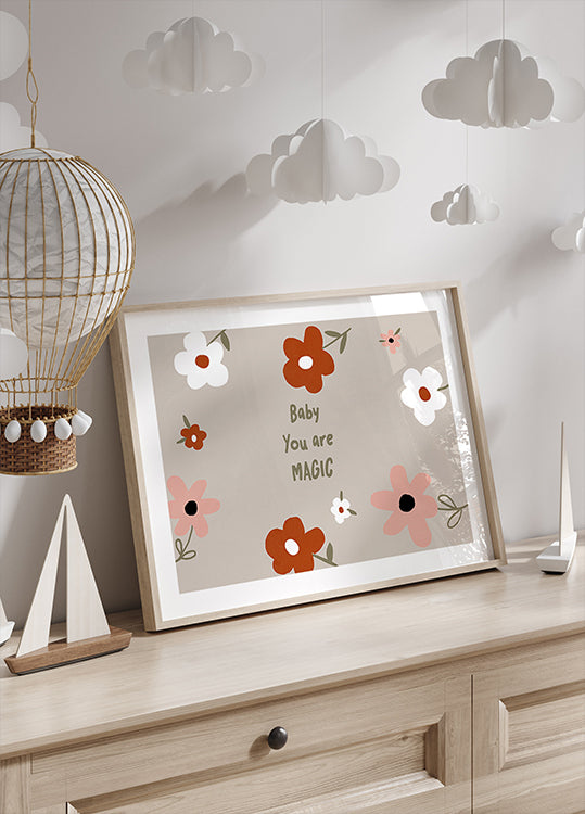 A framed print with a floral design and the text "Baby You are Magic" is displayed on a wooden dresser, with a decorative paper lantern hanging above it.